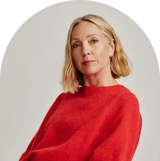 A woman wearing a red sweater is seated comfortably on a chair, exuding a relaxed and casual demeanor.