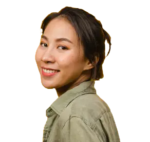 A woman wearing a green shirt smiles warmly, radiating positivity and joy.